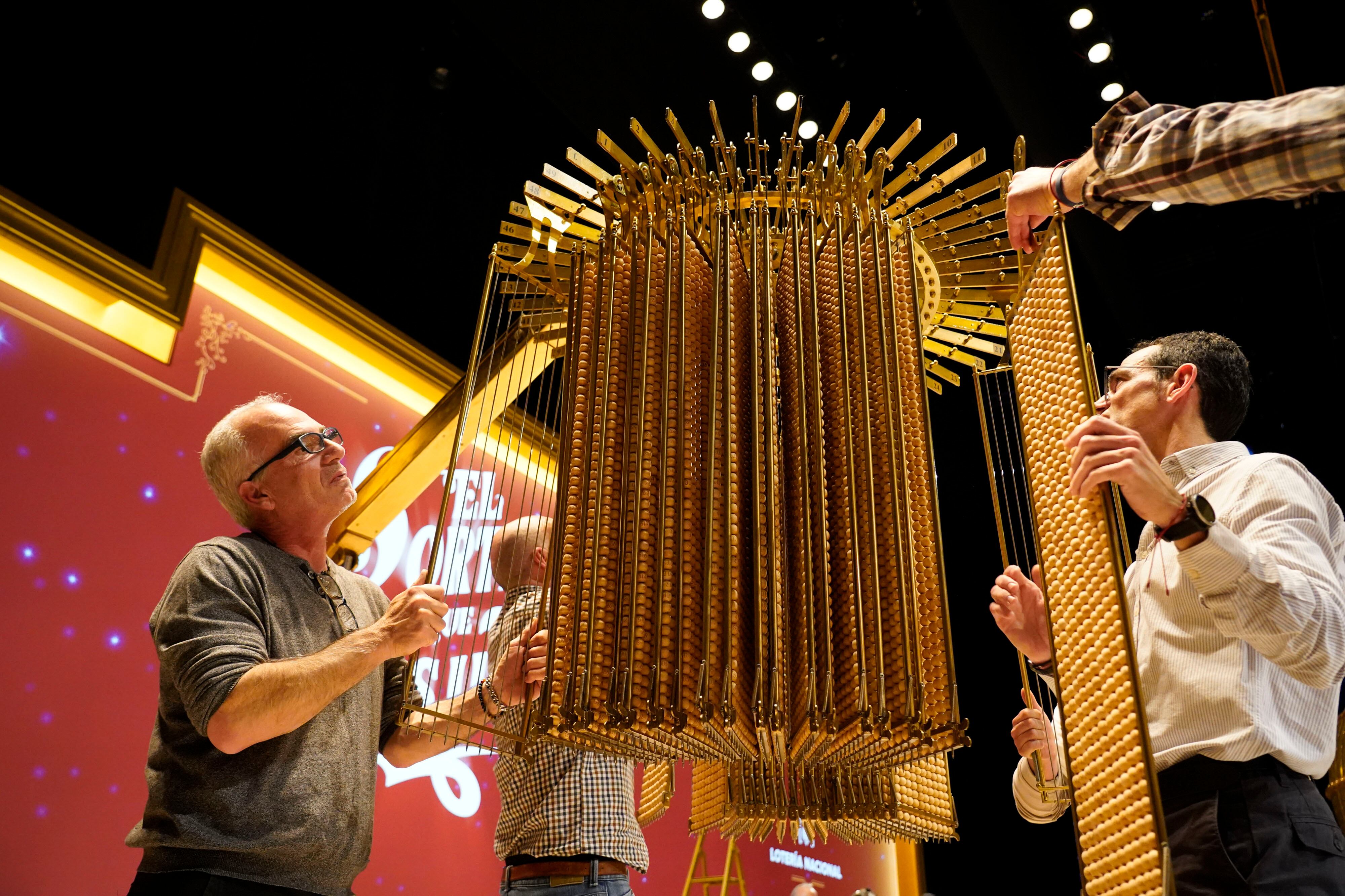 MADRID, 21/12/2025.- Personal de Loterías y Apuestas del Estado ha procedido a la cuelga en los paraguas de las liras que contienen las 100.000 bolas de números, dejando también preparadas las 1.807 bolas de premios que se utilizarán en el Sorteo de mañana. Terminada la cuelga, los claveros de Loterías y Apuestas del Estado han efectuado el cierre y precintado de las puertas del salón del Teatro Real. Miles de españoles estarán pendientes mañana lunes de lo que ya se ha convertido en toda una tradición, y en el pistoletazo de salida de estas fechas navideñas. El Sorteo Extraordinario de la Lotería de Navidad llenará de alegría e ilusión a numerosos hogares repartidos por toda la geografía. EFE/ Loterías Y Apuestas Del Estado SOLO USO EDITORIAL SOLO DISPONIBLE PARA ILUSTRAR LA NOTICIA QUE ACOMPAÑA (CRÉDITO OBLIGATORIO)