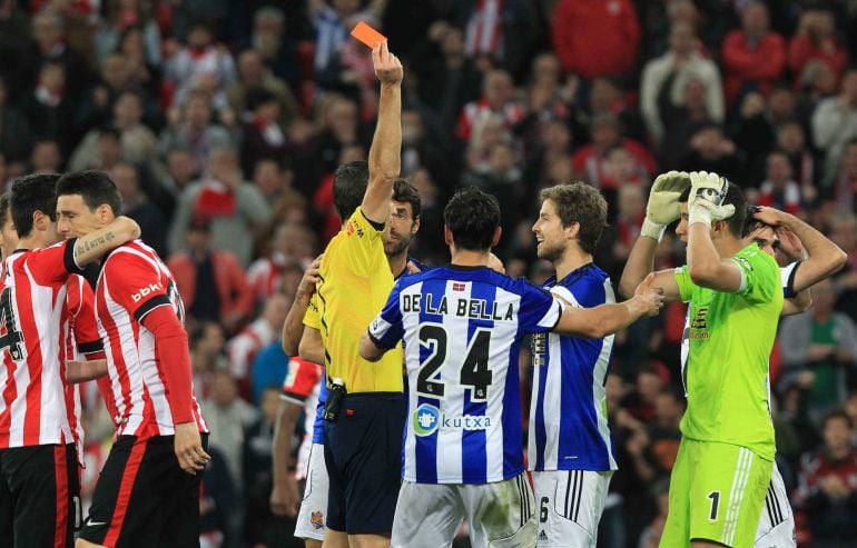 GRA496. BILBAO, 28/04/2015.- El árbitro Martínez Munuera saca tarjeta roja a Mikel González, de la Real Sociedad, durante el encuentro correspondiente a la jornada 34 de Primera División que Athletic Club y Real Sociedad disputan esta noche en el estadio de San Mamés. EFE/Luis Tejido.