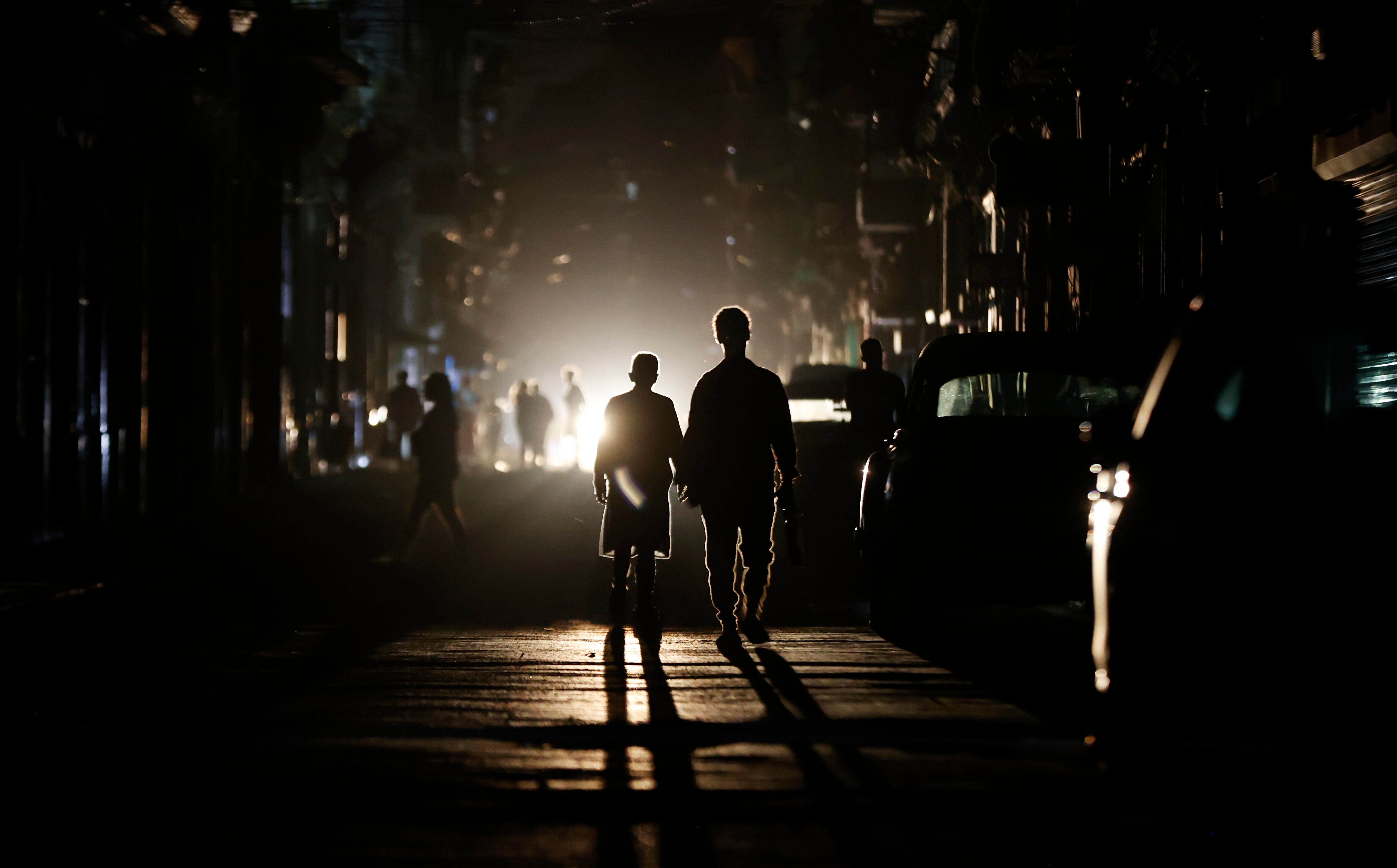 Personas caminan por una calle sin electricidad este sábado, en La Habana (Cuba).