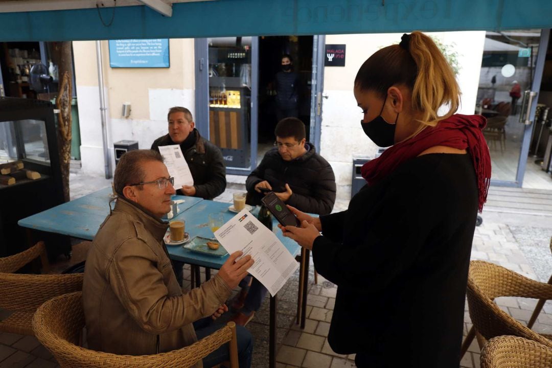 Una camarera pide certificado a los clientes en una mesa en la terraza de un bar durante el primer día de petición de Certificados Covid-19 para la hostelería