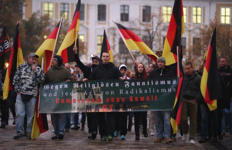 MAGDEBURG, GERMANY - OCTOBER 14:  Supporters of the Magdeburg branch of the Pegida movement carry German flags as they arrive to attend a rally organized by the AfD political party to protest against German Chancellor Angela Merkel&#039;s liberal policy toward