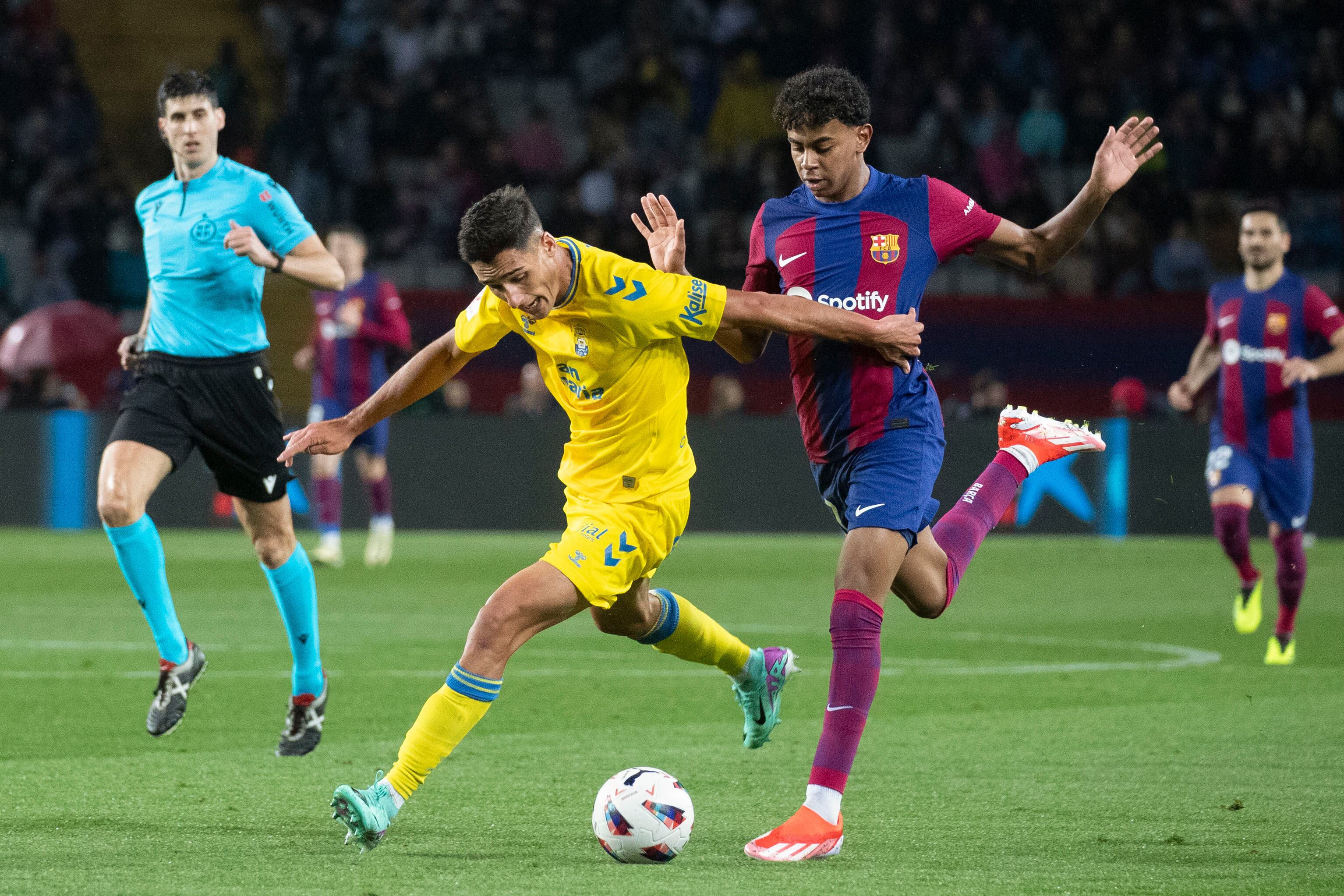 BARCELONA, 30/03/2024.- El delantero del FC Barcelona Lamine Yamal (d) lucha con Sergi Cardona (i), de la UD Las Palmas, durante el partido de la jornada 30 de LaLiga que FC Barcelona y UD Las Palmas disputan hoy sábado en el estadio olímpico Lluís Companys. EFE/ Marta Pérez
