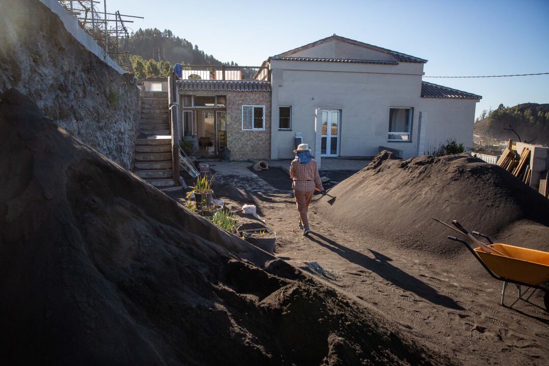 Una mujer retira cenizas del interior de su casa ubicada en el barrio de Las Manchas, en el municipio palmero de Los Llanos de Aridane, afectado por la erupción del volcán de Cumbre Vieja desde el 19 de septiembre de 2021