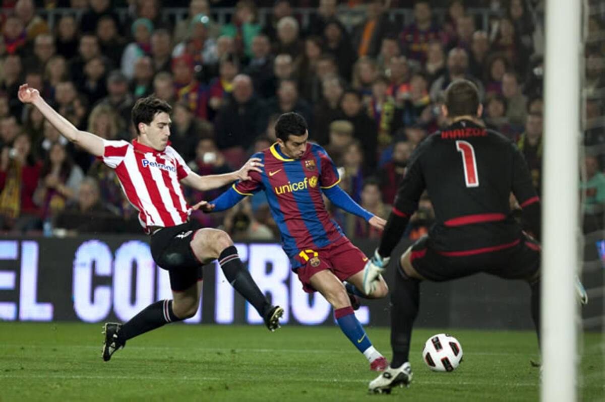 El delantero del FC Barcelona Pedro Rodríguez (c) chuta a portería ante el portero y el defensa del Athletic de Bilbao Gorka Iraizoz (d) y Andoni Iraola, respectivamente, durante el partido correspondiente a la vigésimo cuarta jornada del Campeonato Nacio