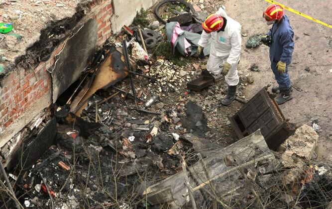 Dos bomberos de los equipos de extinción de incendios de Barcelona inspeccionan el solar de la calle Bilbao 134, donde se ha producido un incendio en una chabola en el que han muerto cuatro personas