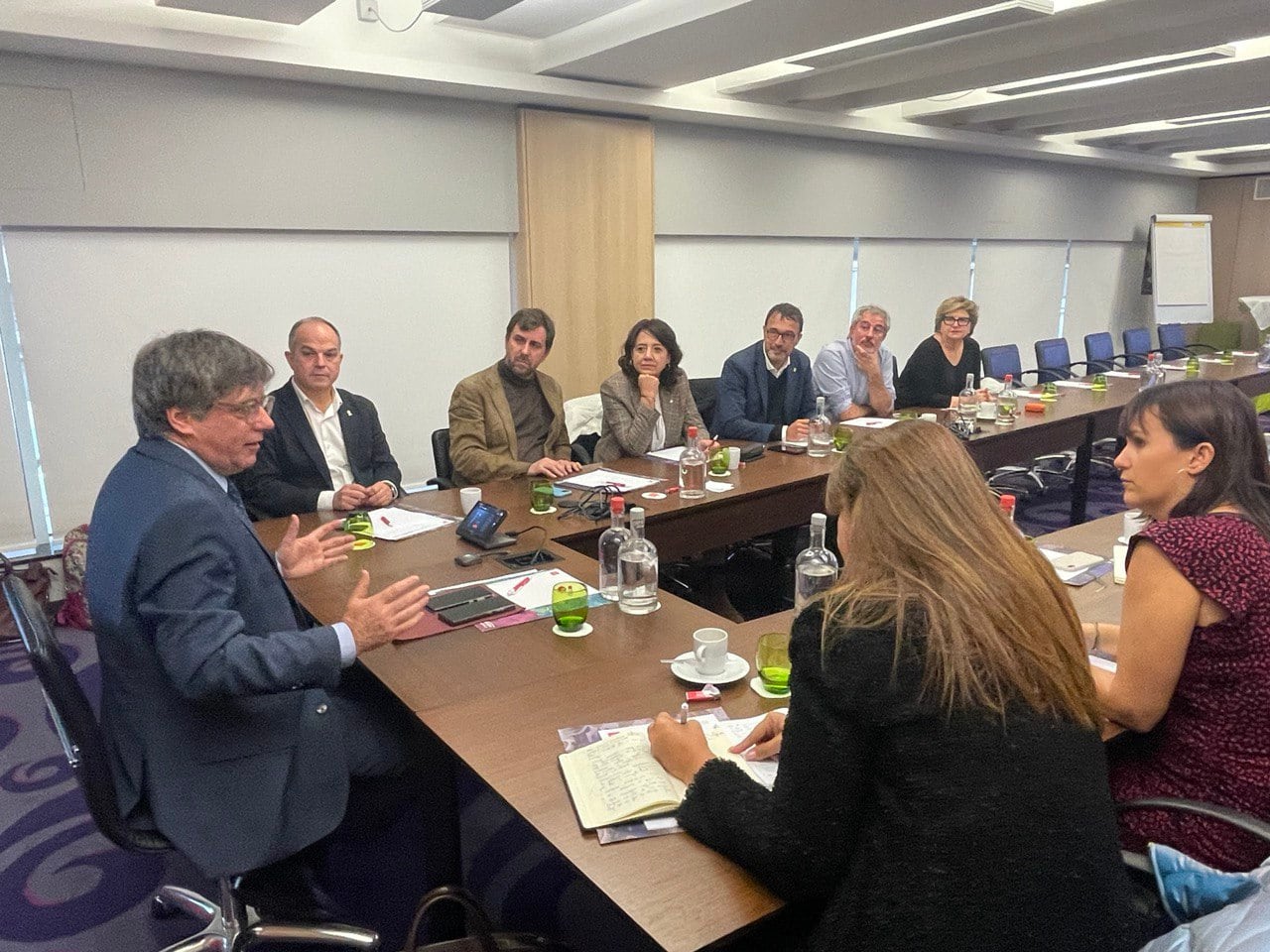 El expresidente de la Generalitat Carles Puigdemont (i) junto a Jordi Turull (i-fondo) y Laura Borrás (d), entre otros miembros de la cúpula de JxCat, durante la reunión este jueves en Bélgica