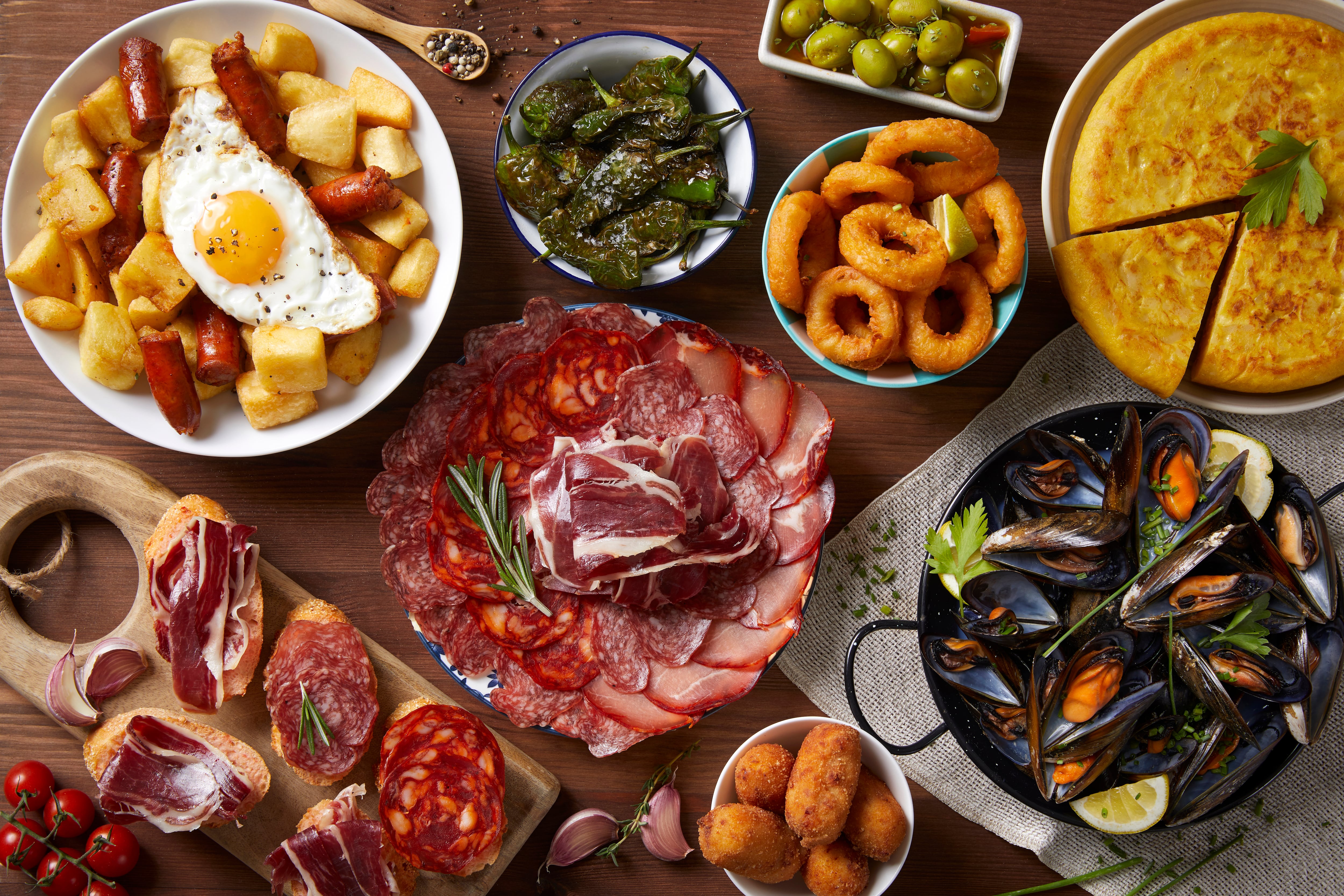 Diferentes platos típicos de la gastronomía española juntos en una mesa.