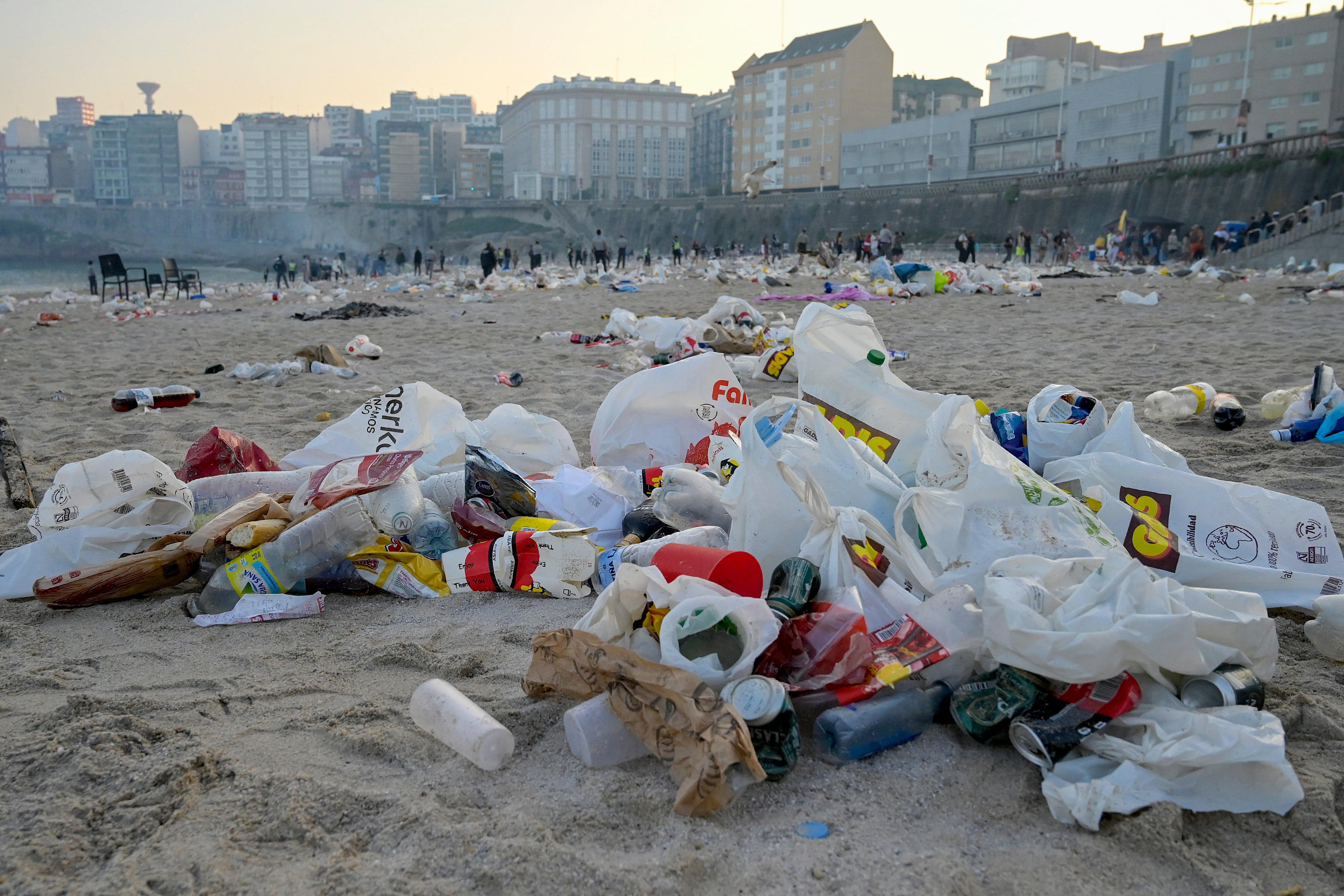 LA CORUÑA, 24/06/2023.- La playa del Orzán en A Coruña amanece este sábado cubierta de basura generada durante la noche de San Juan mientras la policía y refuerzos de seguridad privada conminan a los presentes a abandonar el arenal. EFE/ Moncho Fuentes
