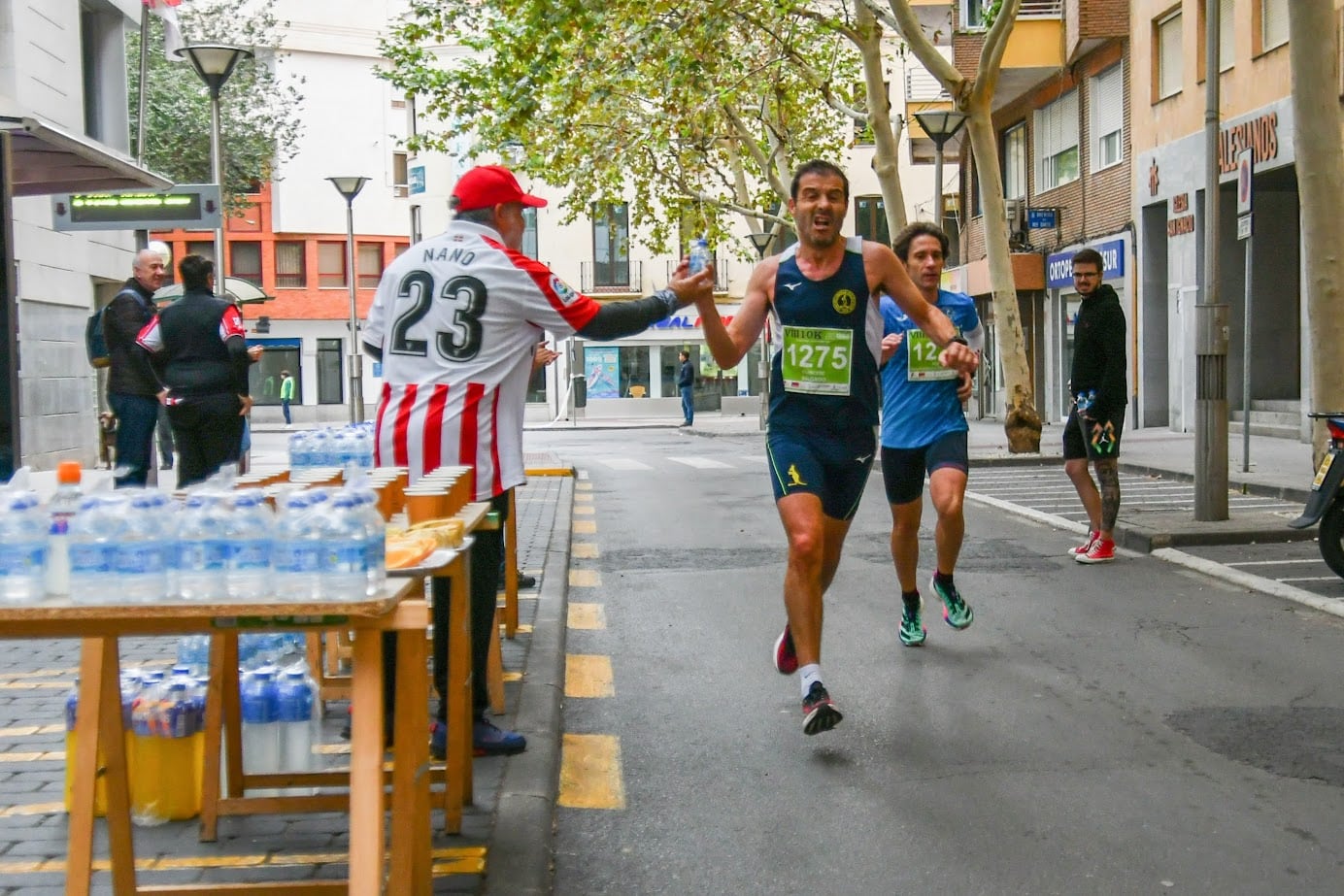 Momento en el que un voluntario entrega agua a los atletas