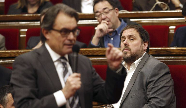 GRA210. BARCELONA, 17/12/2014.- El presidente de ERC, Oriol Junqueras (i), escucha al presidente de la Generalitat, Artur Mas (de espaldas), durante la sesión de control al gobierno catalán, en el último pleno del Parlament del año, quien afronta la sesión con el margen de un mes que le ha dado ERC al asegurarle su apoyo ante las enmiendas a la totalidad del proyecto de Presupuestos, que hoy celebra su primera tramitación, de cara a poder negociar unas plebiscitarias. EFE/Alejandro García
