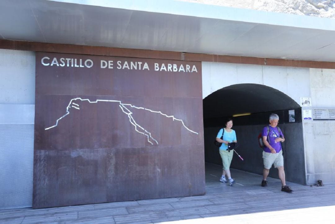 Unos turistas salen del túnel que da acceso a los ascensores del Castillo Santa Bárbara