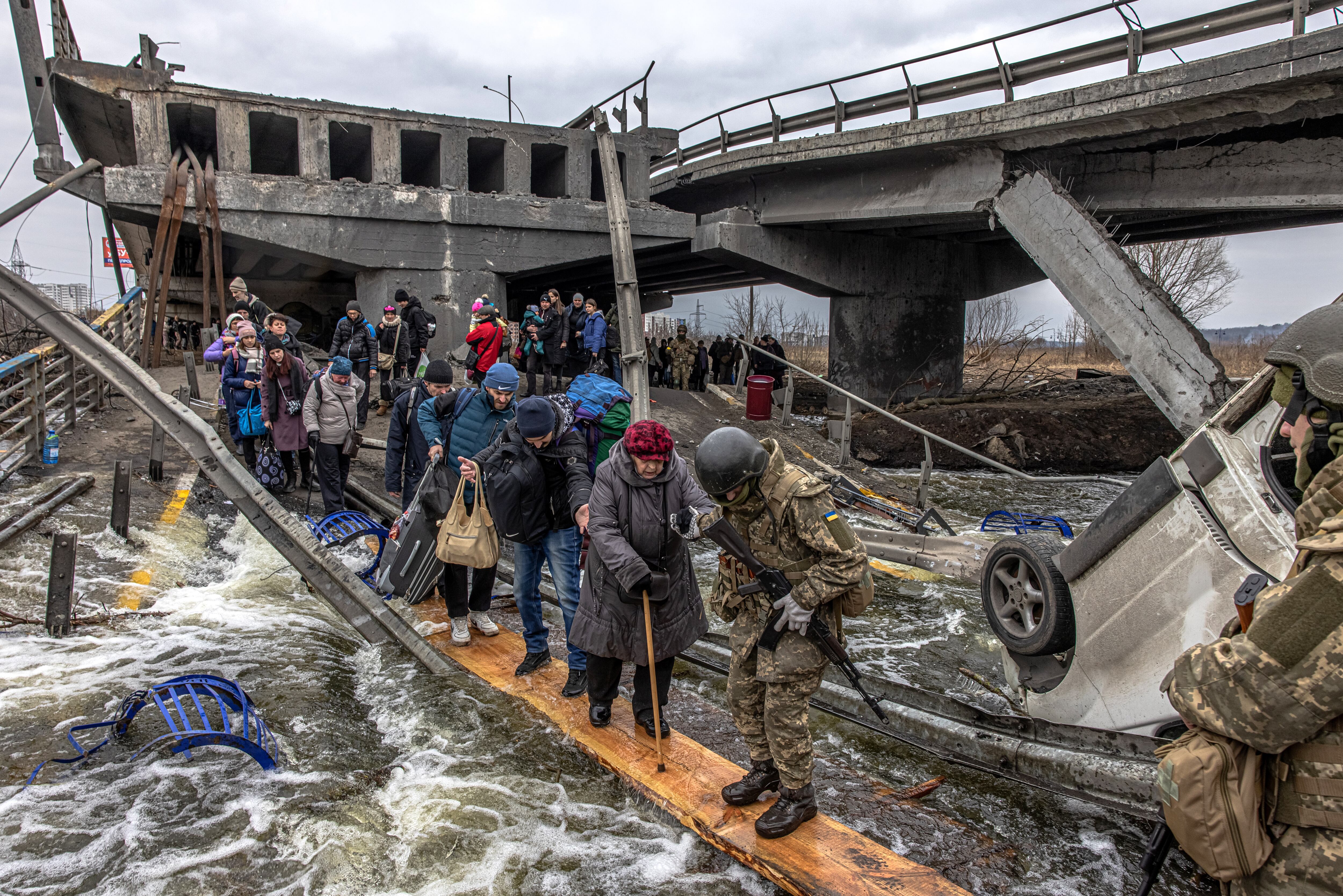 Civiles cruzan un puente destruido mientras huyen del asedio en la ciudad de Irpin, a unos 20 km de la capital, en Ucrania. Los ucranianos que han tenido que dejar su país a consecuencia de la guerra con Rusia se elevan ya a 1,73 millones, una cifra que crece mientras lo hacen también las dificultades para poder salir, con Moscú que continúa sus ataques sobre algunas de las ciudades más pobladas. EFE/ Roman Pilipey