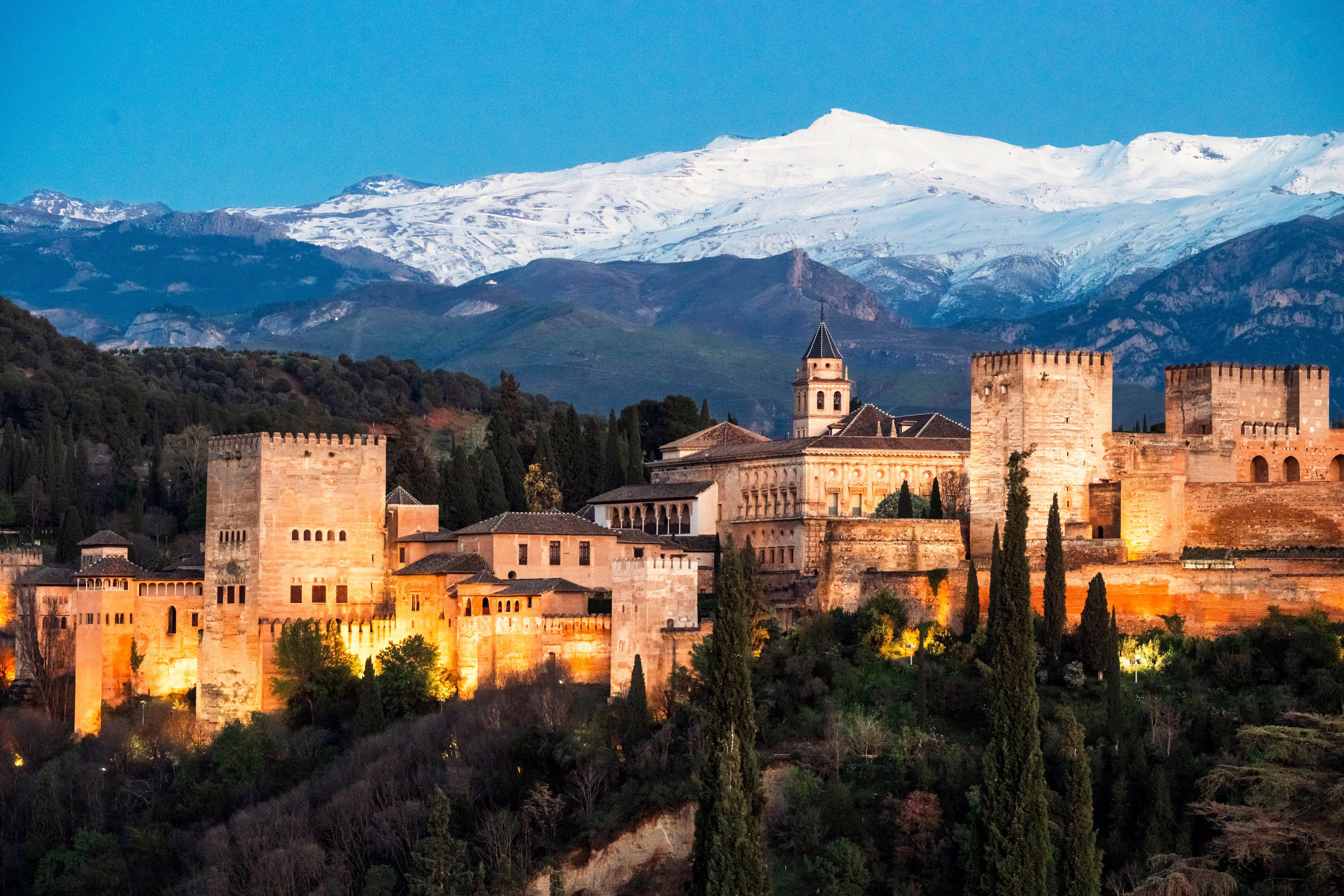 La Alhambra de Granada, con Sierra Nevada al fondo, en una imagen de la puesta de sol del 4 de abril de 2024 que puede contemplarse desde la Iglesia de Santa María de la Aurora y San Miguel en pleno barrio morisco del Albaicín