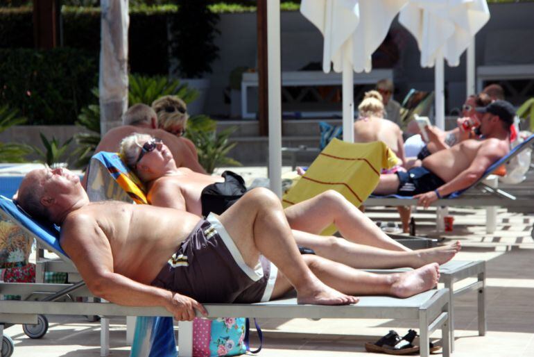 Una parella de turistes estrangers prenent el sol en unes gandules, junt amb altres turistes a la zona de piscina en un important càmping de la Costa Daurada, a Cambrils, el 21 de juny de 2016. (Horitzontal)