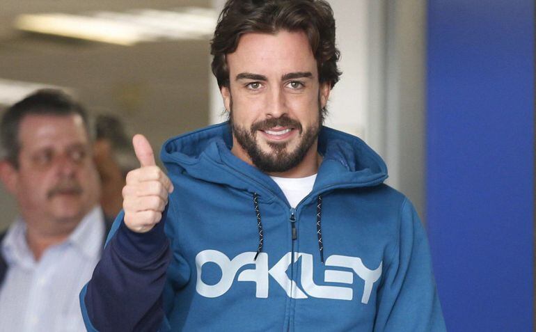 El piloto español Fernando Alonso saluda a la prensa al salir del hospital tras recibir el alta hospitalaria