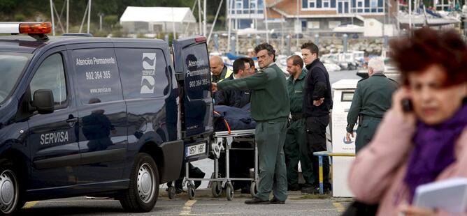 Las fuerzas de seguridad introducen en un furgón funerario el cuerpo de uno de los marineros fallecidos en el naufragio de A Coruña