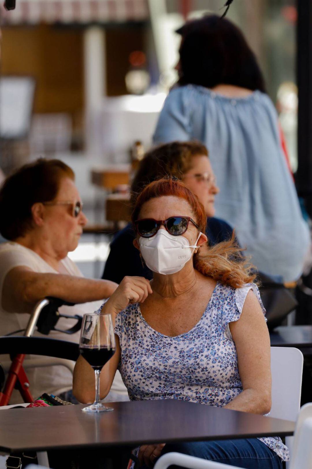 Una mujer toma una copa en una terraza
