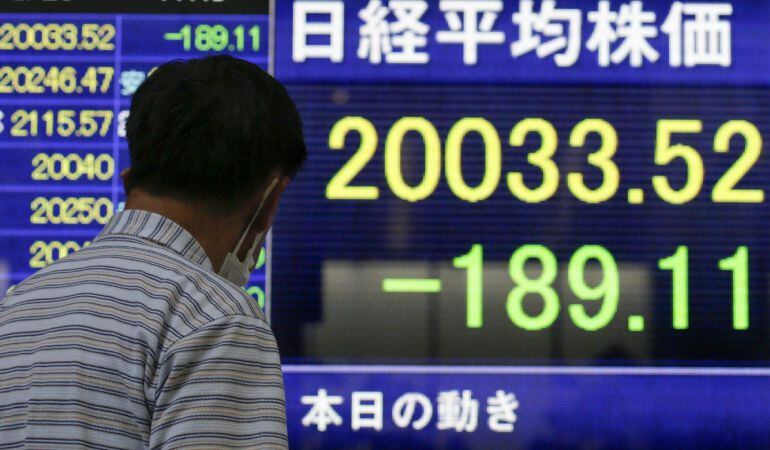 Un peatón observa la información bursátil mostrada en unas pantallas en el centro de Tokio