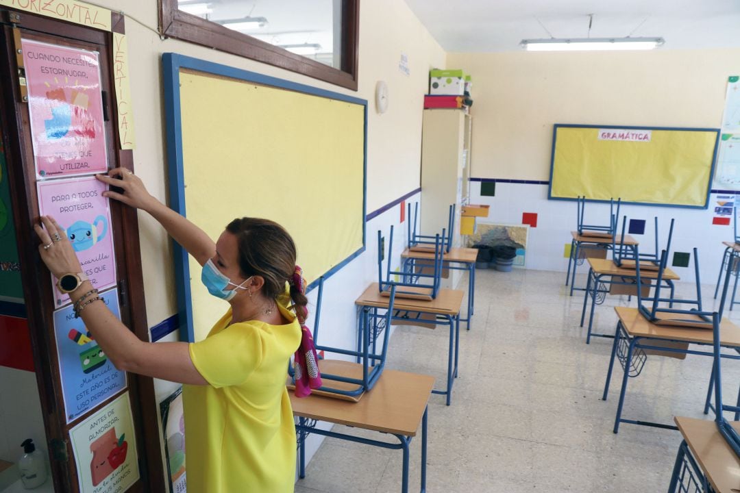 Una profesora coloca carteles de medidas preventivas ante el COVID-19 