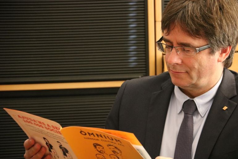 El expresidente Carles Puigdemont lee un documento de Òmnium en Bruselas. 