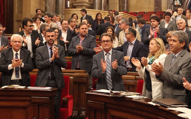 El presidente de la Generalitat, Artur Mas, aplaude rodeado de varios miembros de su gobierno, tras la aprobación,  en el pleno del Parlamente de Cataluña, de una resolución pactada por los cuatro partidos que promueven la consulta para impulsar la cita d