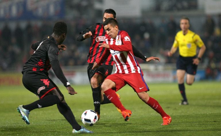 El delantero argentino del Atlético de Madrid Ángel Correa lucha el balón con el guineano Eliseu Cassama y Ramon Folch