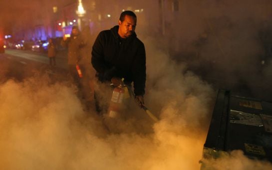 Un joven intenta apagar uno de los fuegos que se iniciaron durante la segunda noche de protestas en Ferguson