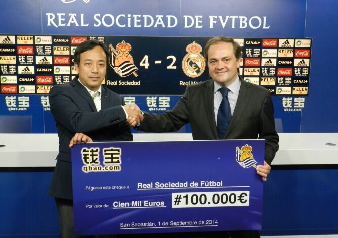 Li Qunfeng, el representante de Qbao.com, y Jokin Aperribay, presidente de la Real, posan con el cheque.