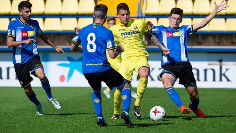 El jugador amarillo Dani Raba disputa el balón con varios jugadores del Hércules durante un partido con el filial