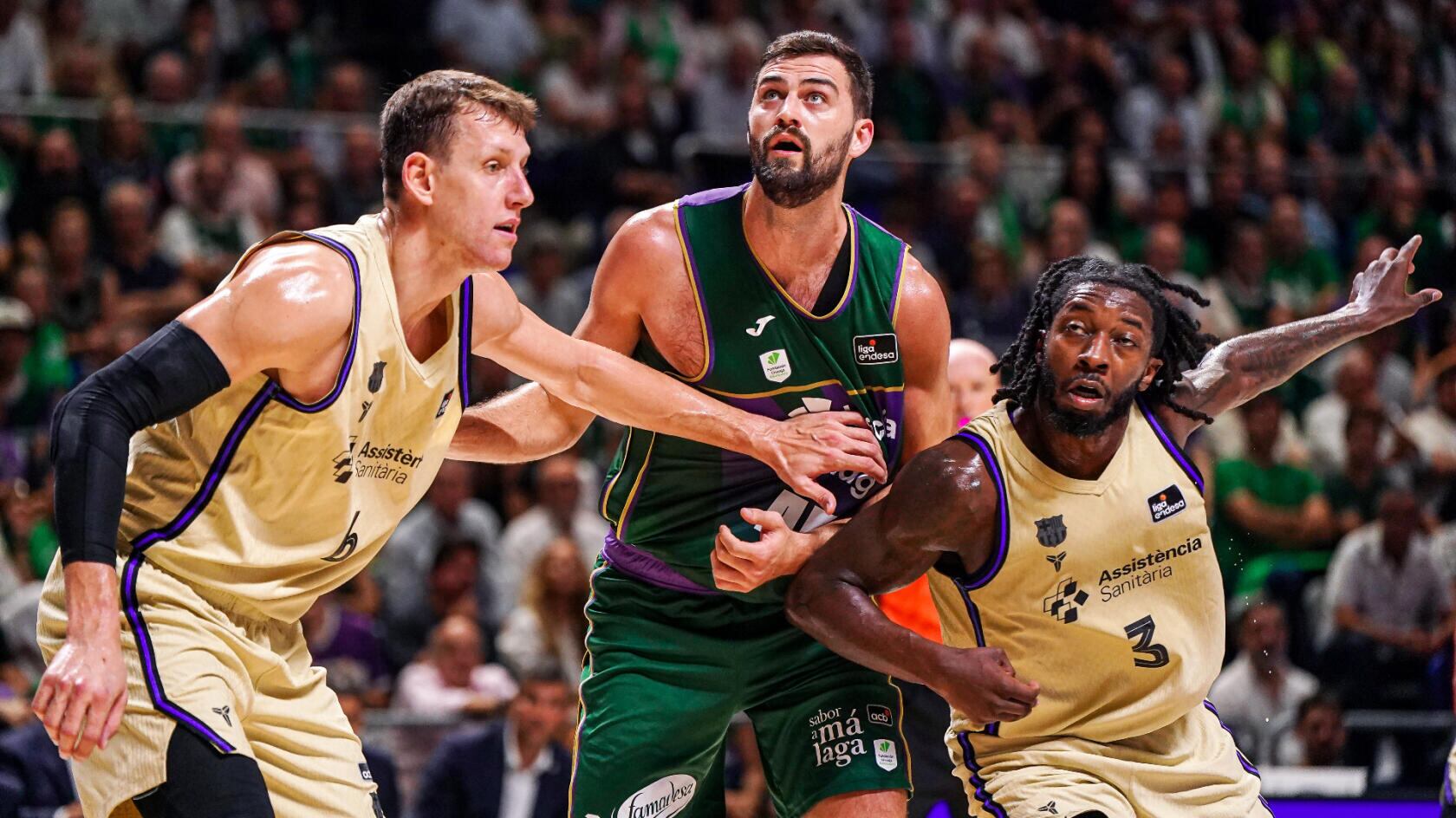 El pívot del Unicaja David Kravish en una acción con dos jugadores del Barça