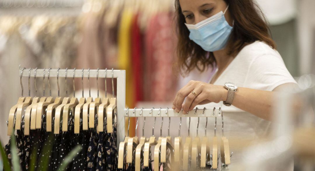 Una mujer con mascarilla en una tienda de ropa