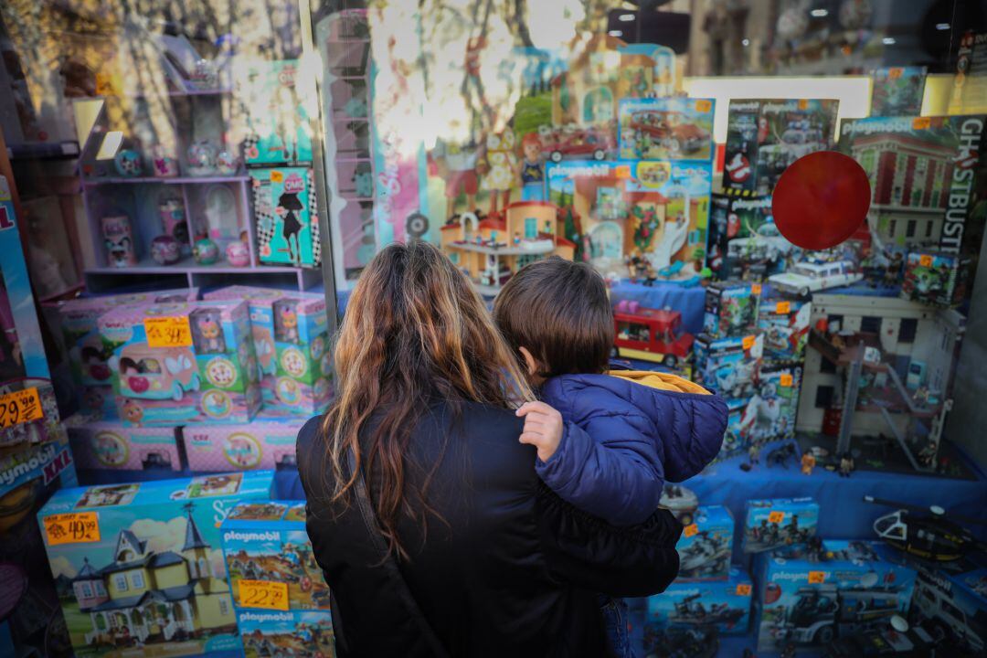 Una mujer y un niño observan un escaparate de una juguetería