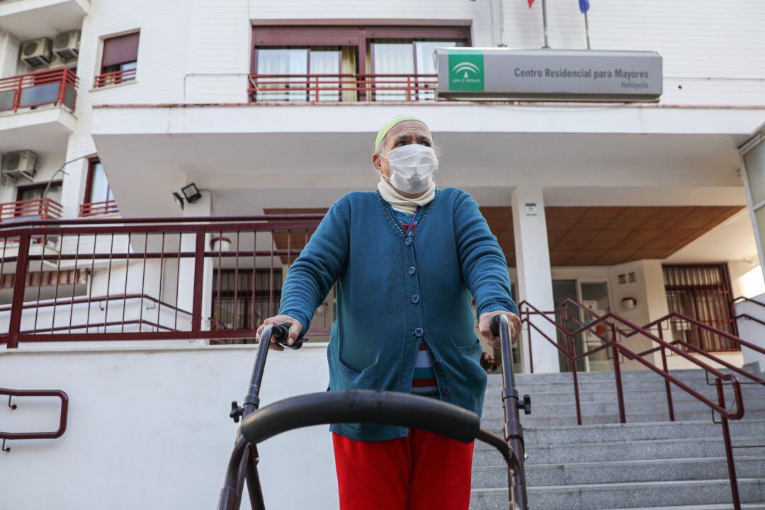 Una anciana sale de un centro residencial para mayores.