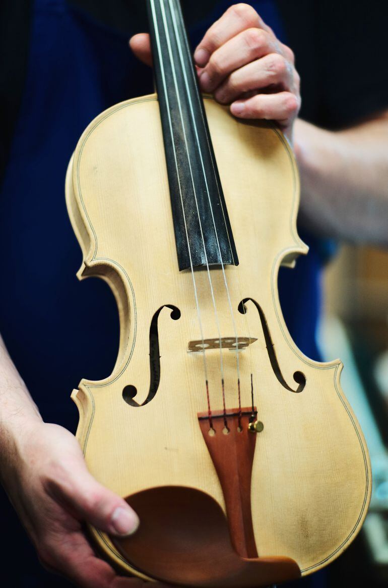 LIVERPOOL, ENGLAND - OCTOBER 24: Violin and bow maker Michael Phoenix inspects one of his traditionally made violins at his workshop on October 24, 2014 in Liverpool, England. Michael Phoenix is a traditional maker, repairer and restorer of violins, violas, cellos and bows. Michael trained at he famous Newark School of Violin Making and only uses traditional methods in their construction. A single violin made by Michael can take up to 250 hours of of meticulous craftmanship following the traditional techniques of the old Italian Cremonese masters using no power tools. (Photo by Christopher Furlong/Getty Images)