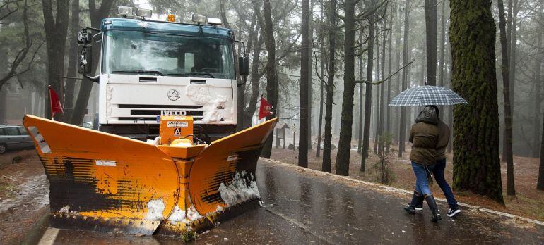 Una pareja pasa por delante de un quitanieves en la carretera cortada al tráfico que conduce al Parque Nacional de El Teide donde se ha producido la primera gran nevada del año