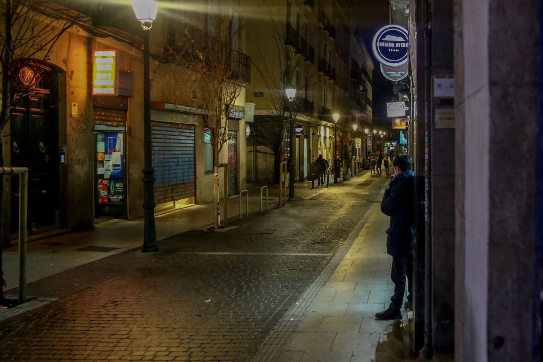 Un joven contempla una calle con un restaurante cerrado durante el primer día del toque de queda a las 10 de la noche, en Madrid.