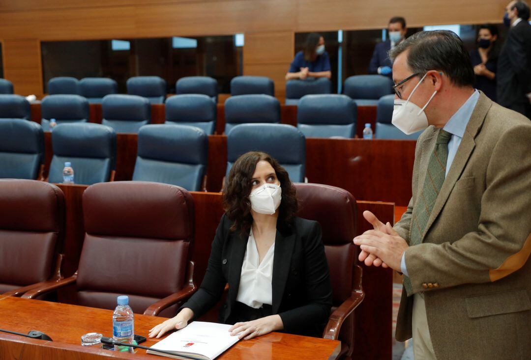 El diputado del PP Alfonso Carlos Serrano conversa con la presidenta regional Isabel Díaz Ayuso, durante el pleno celebrado este jueves en la Asamblea de Madrid., en Madrid (España), a 28 de mayo de 2020.