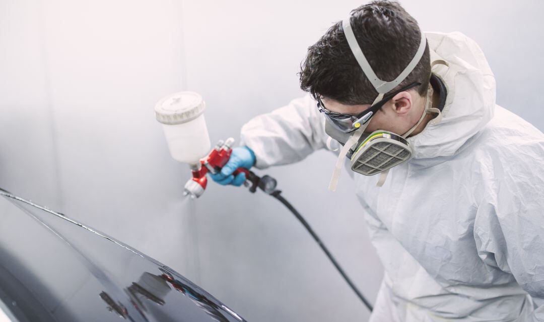 Un hombre pintando un coche.