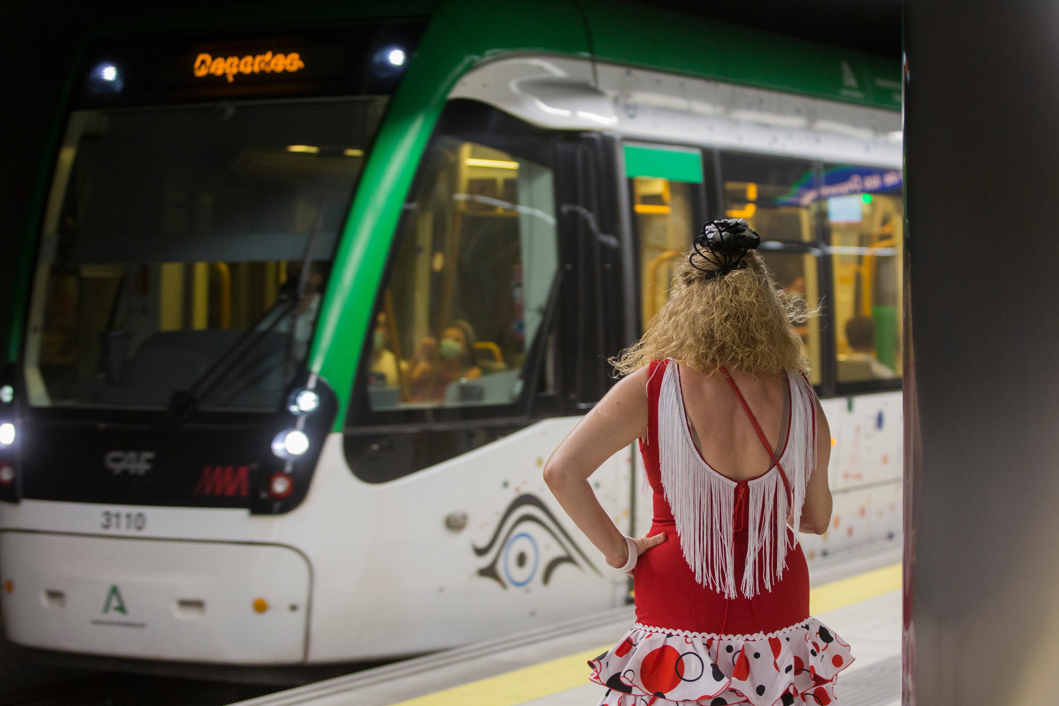 Una mujer vestida de flamenca espera al metro de Málaga