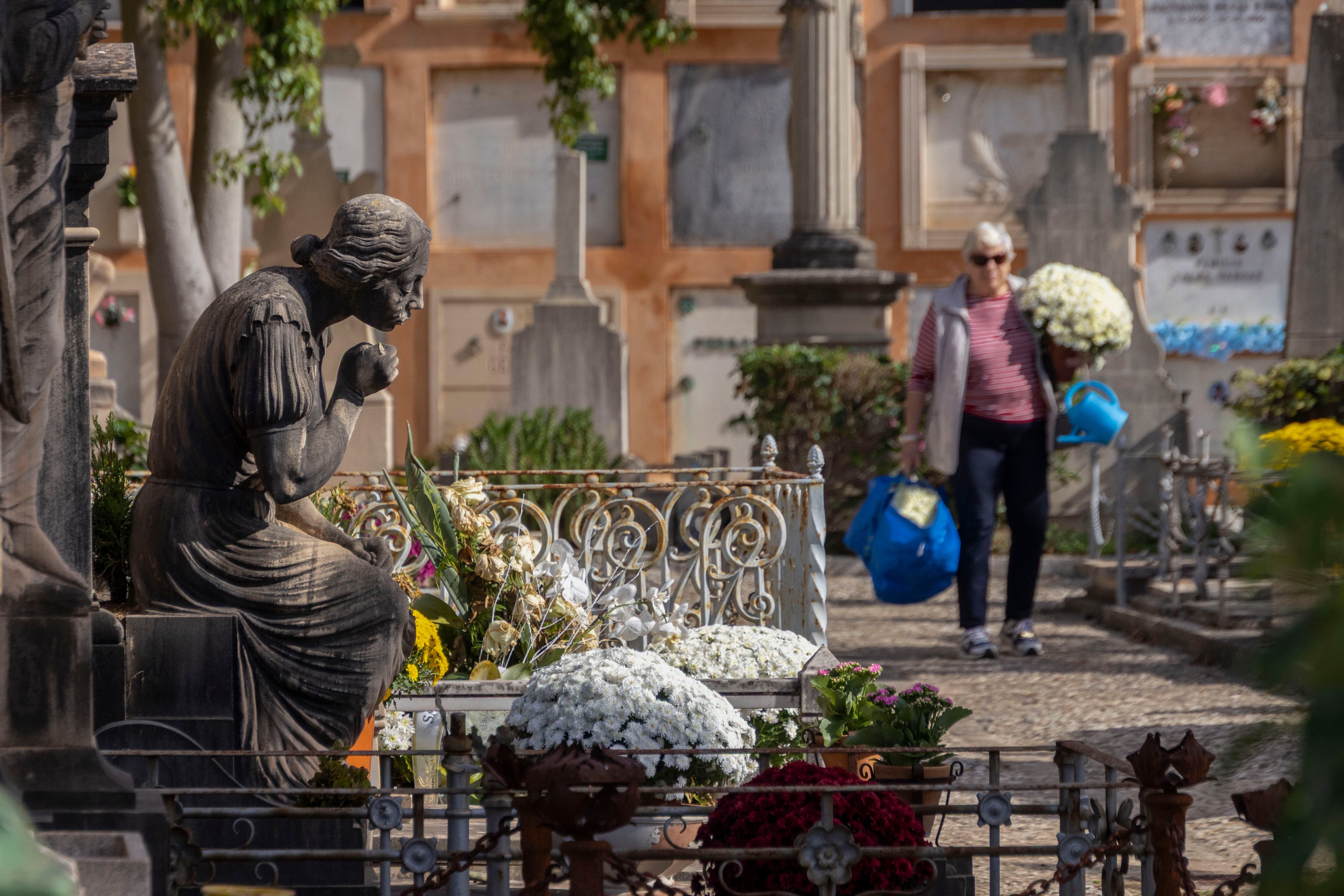 PALMA DE MALLORCA, 31/10/2025.- Una mujer porta flores en el cementerio de Palma este viernes, vísperas de la festividad de Todos Los Santos. EFE/CATI CLADERA
