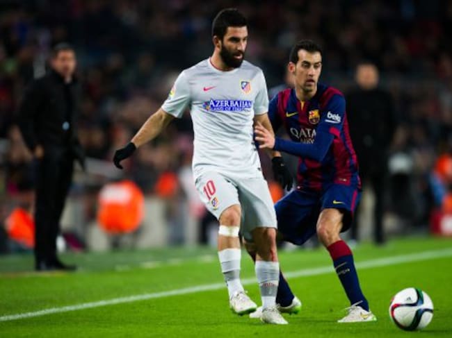 El centrocampista turco trata de regatear a Busquets