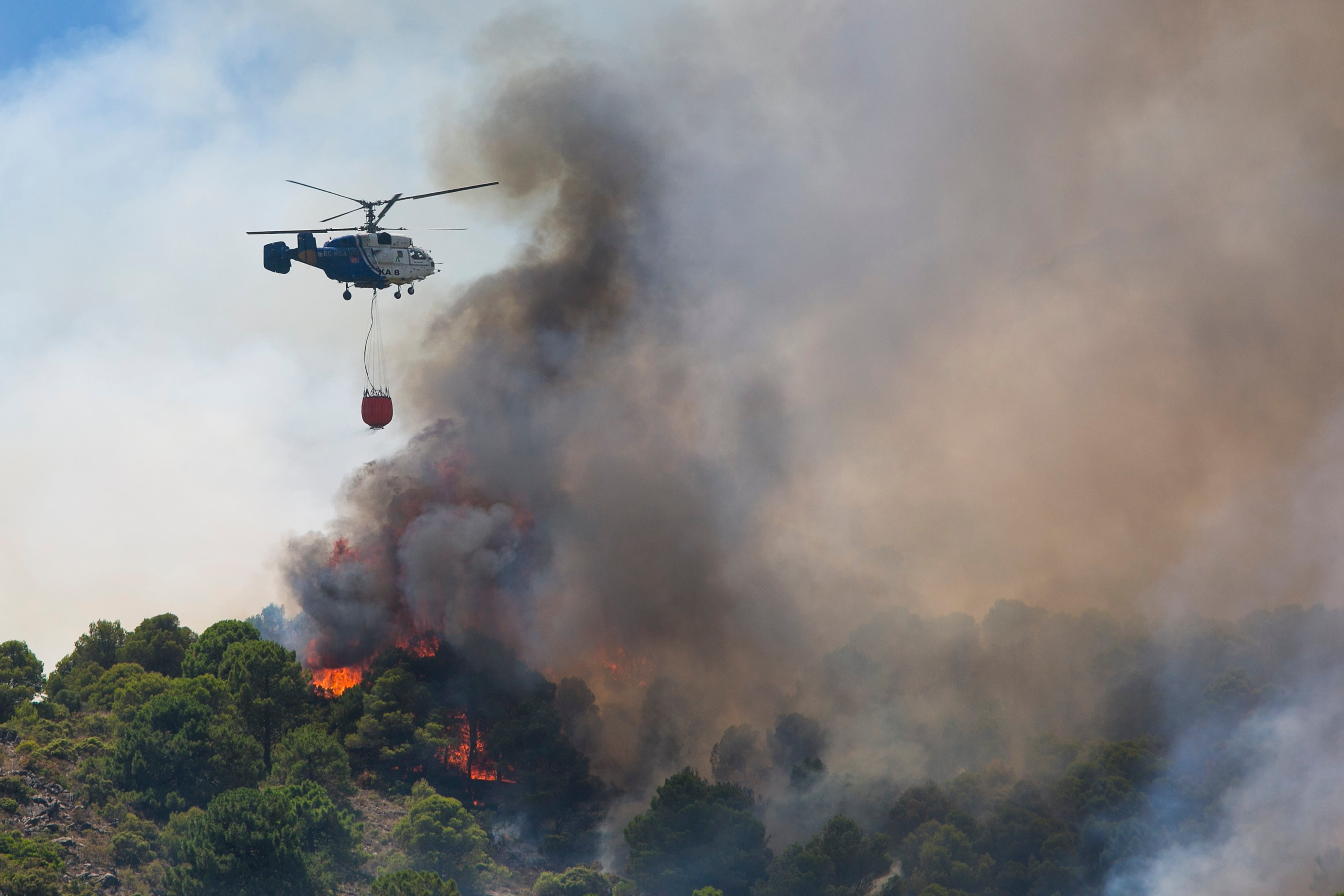 ALHAURÍN DE LA TORRE (MÁLAGA) 16/07/2022.- Un helicóptero del servicio de bomberos trabaja en el incendio declarado en la sierra de Mijas, Málaga, este sábado. EFE/Álvaro Cabrera