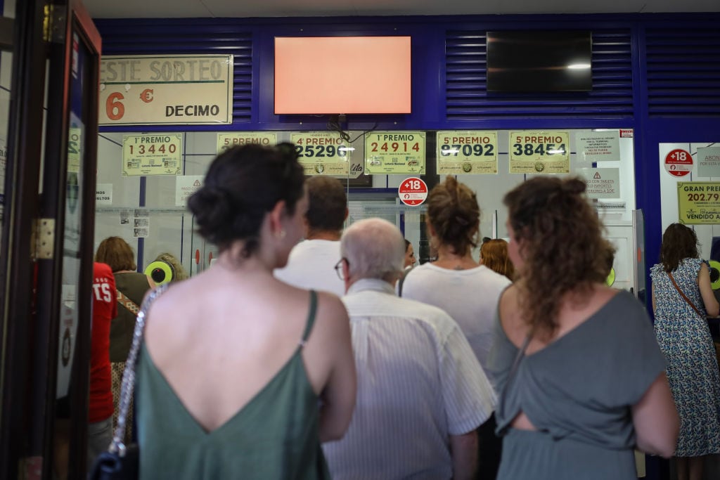 Personas hacen cola para comprar décimos de la Lotería de Navidad.