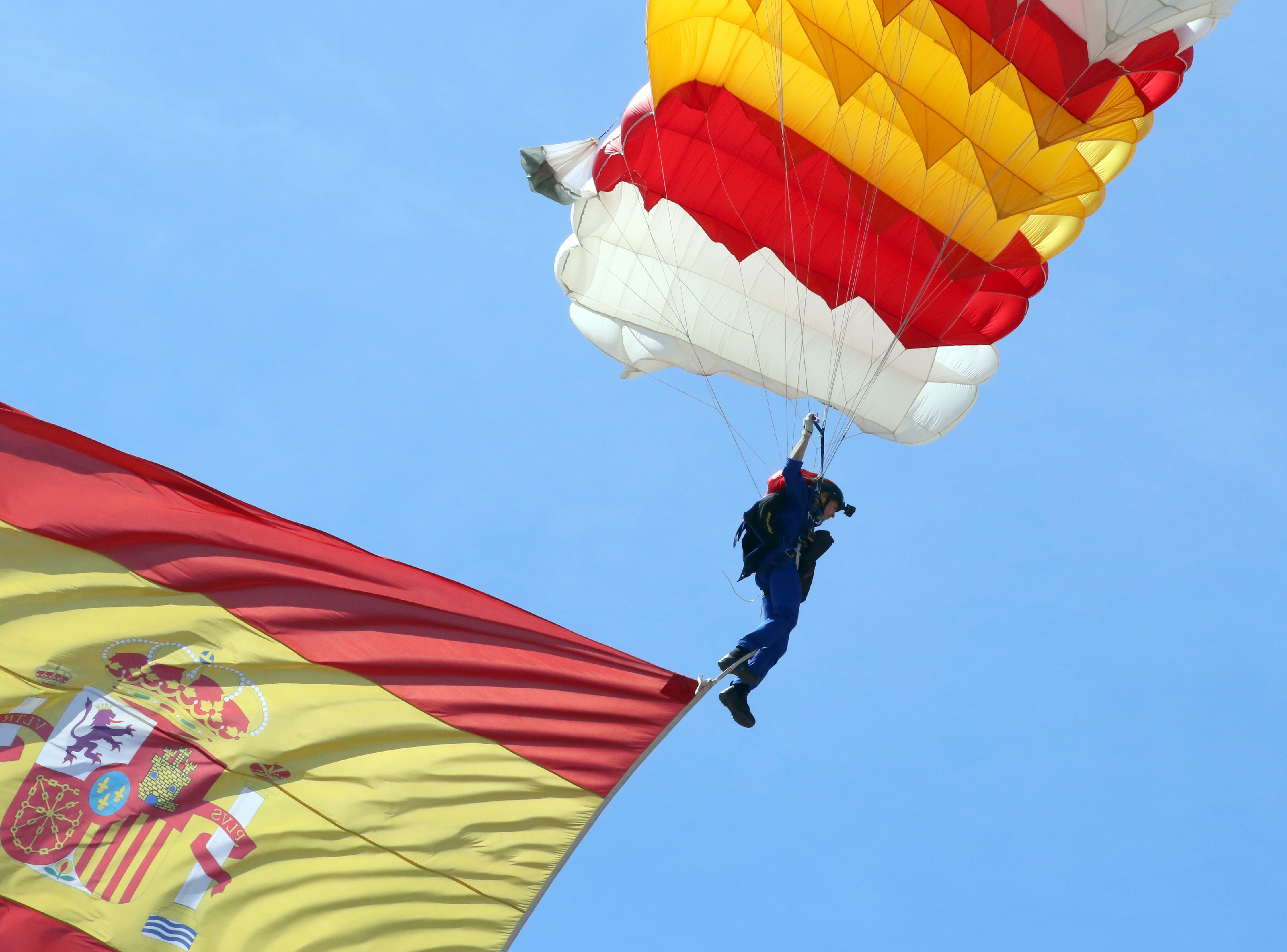 La cabo paracaidista Carmen Gómez Hurtado desciende con una bandera de España de 15 kilos de peso y 53 metros cuadrados durante el desfile del Día de las Fuerzas Armadas este sábado en Granada. Es la primera vez que una mujer asume esta responsabilidad en esta celebración, coincidiendo con el 35 aniversario de la entrada de la mujer en las Fuerzas Armadas