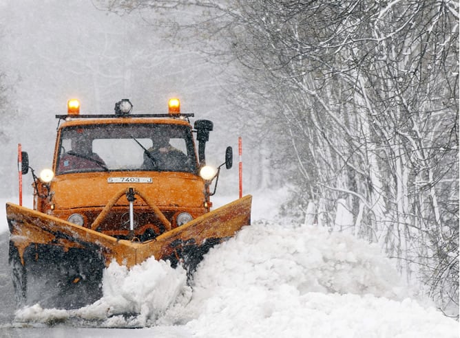 Una pequeña maquina retira la nieve de la calzada para poder acceder al pueblo de Abiada, en Cantabria