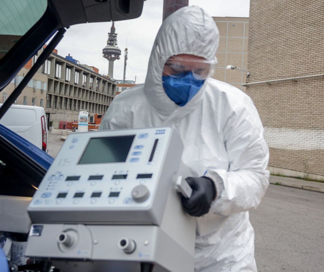 Un técnico protegido con un traje, guantes y mascarilla porta un respirador 