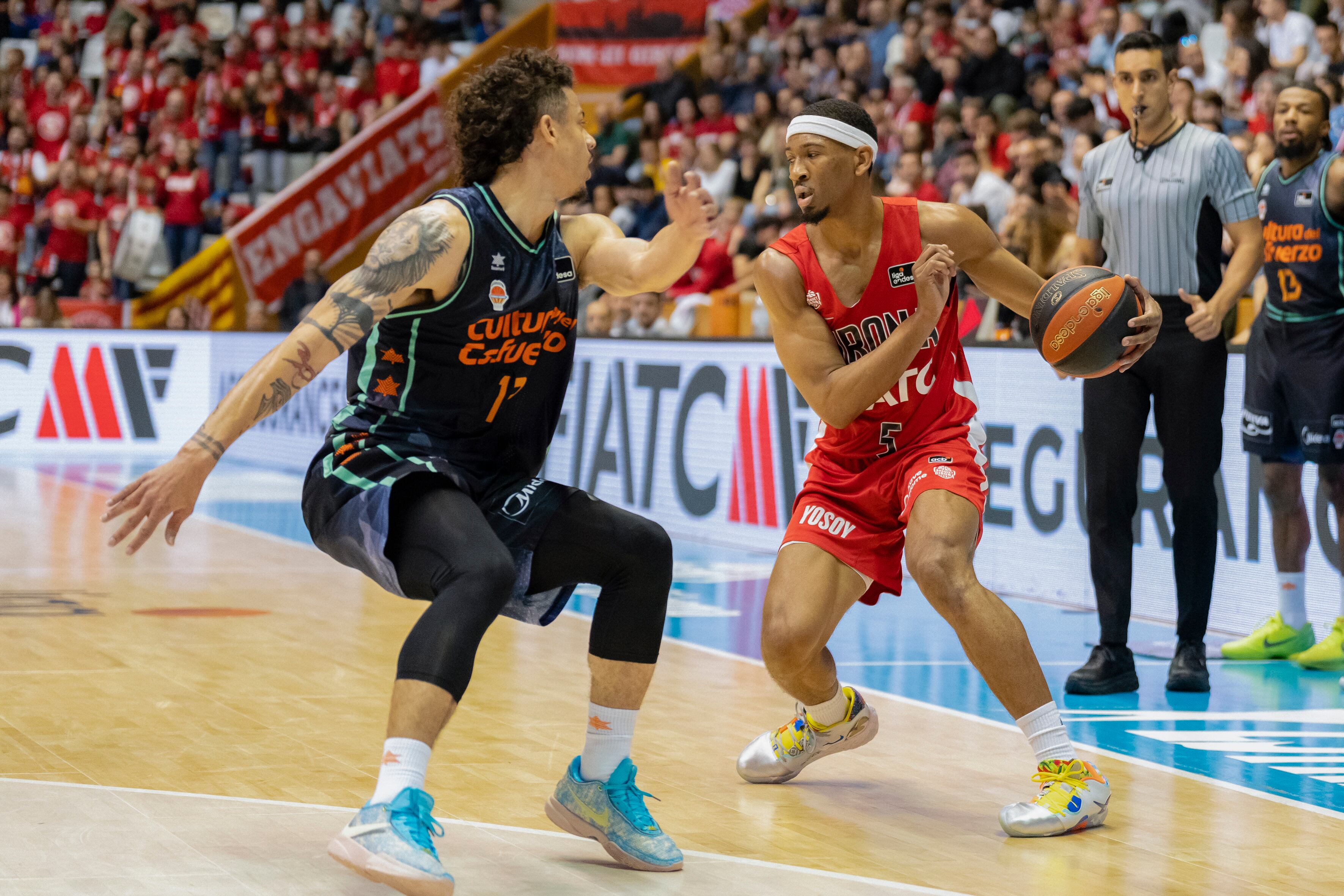 GIRONA, 12/03/2023.- El base estadounidense del Valencia, Jonah Radebaugh (i) lucha por el balón con el alero estadounidense Kameron Taylor (d) del Basquet Girona durante el partido correspondiente a la Liga ACB Endesa disputado este domingo en el pabellón de Fontajau de Girona. EFE/David Borrat