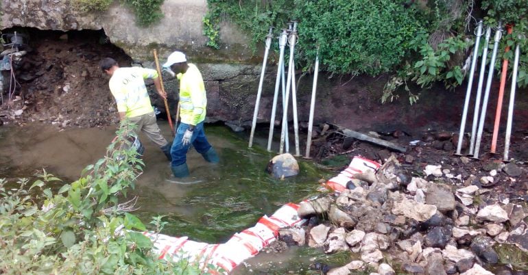 Operaris preparant l'actuació en un esvoranc que amenaça els fonaments d'un taller.