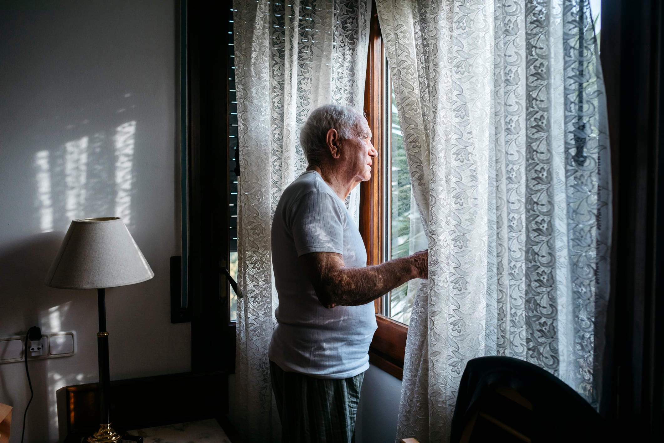 Un hombre que vive solo observa la actividad de la calle desde su ventana.