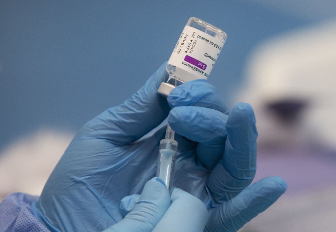 Una profesional sanitaria sostiene una jeringuilla con un vial de la vacuna contra la COVID-19 de AstraZeneca